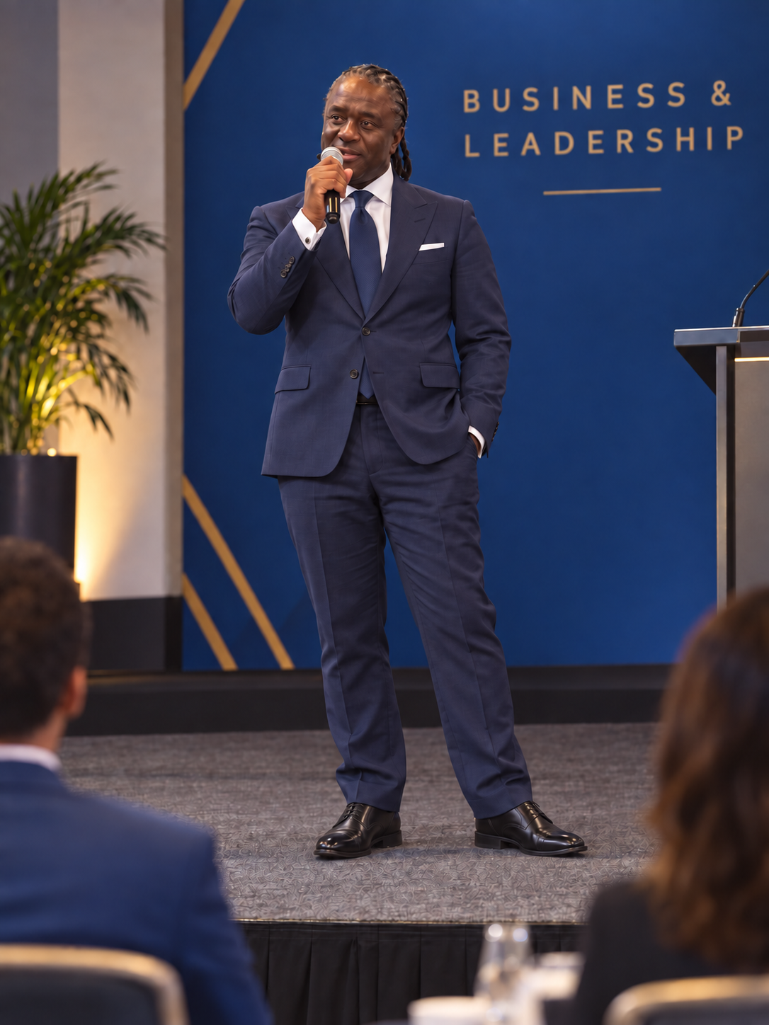 Edited portrait of Colin Kasambira in a navy suit in a seminar setting